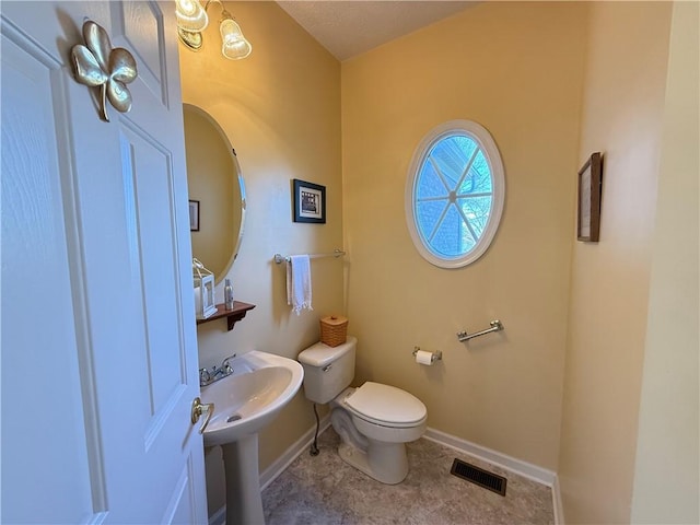 half bath featuring visible vents, baseboards, and toilet