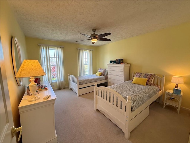bedroom with light carpet, a ceiling fan, and a textured ceiling