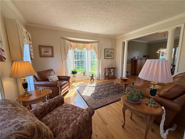 living area with an inviting chandelier, crown molding, decorative columns, wood finished floors, and a textured ceiling