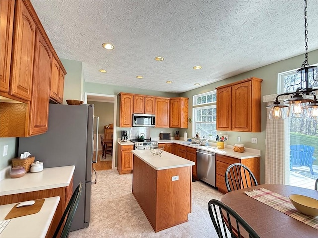 kitchen with a kitchen island, brown cabinets, appliances with stainless steel finishes, and a healthy amount of sunlight