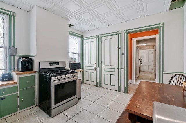 704 E 10th Ave, Munhall, PA 15120 - kitchen with light tile patterned floors, wood counters, green cabinetry, and gas range