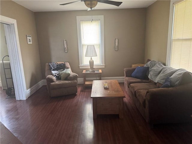 living area featuring baseboards, a ceiling fan, and dark wood finished floors