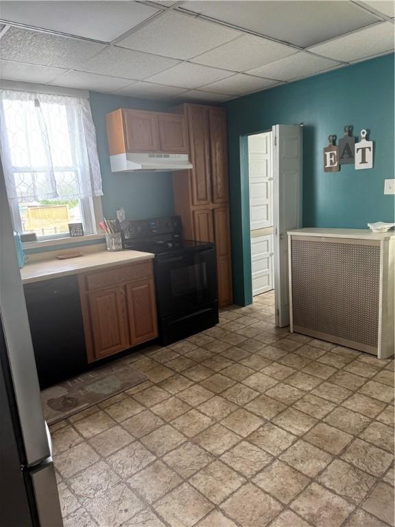 kitchen with light countertops, a drop ceiling, under cabinet range hood, and black electric range oven