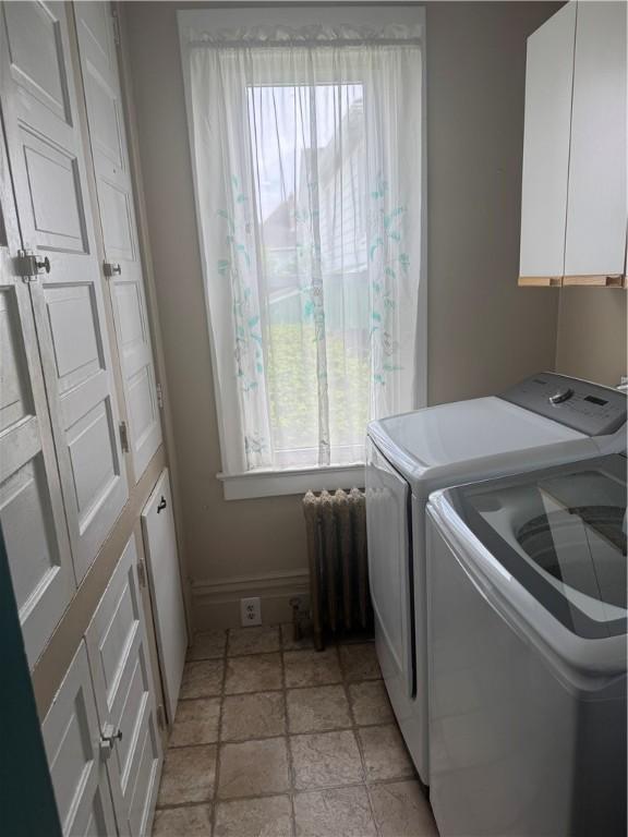 laundry area featuring cabinet space, baseboards, a healthy amount of sunlight, and radiator heating unit