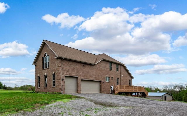 view of side of home featuring a wooden deck, an attached garage, gravel driveway, and brick siding