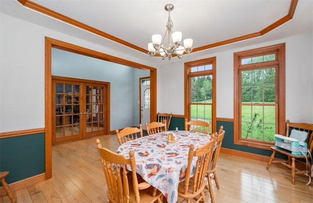 dining space featuring ornamental molding, baseboards, light wood-type flooring, a chandelier, and french doors