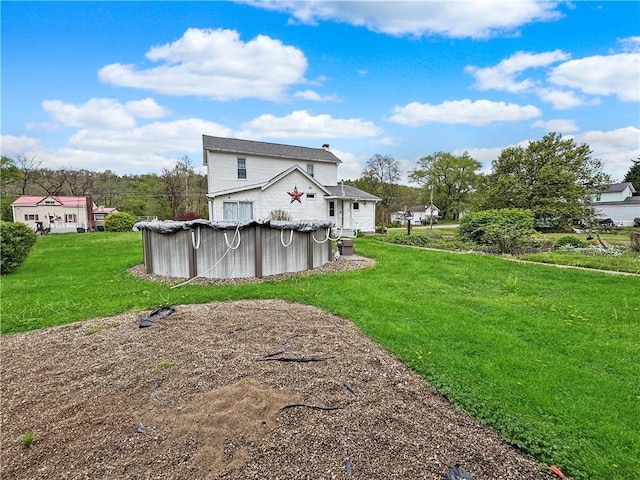 rear view of house featuring a lawn and a covered pool