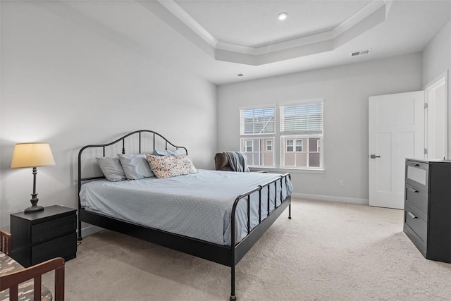 bedroom with a tray ceiling, light colored carpet, baseboards, and visible vents