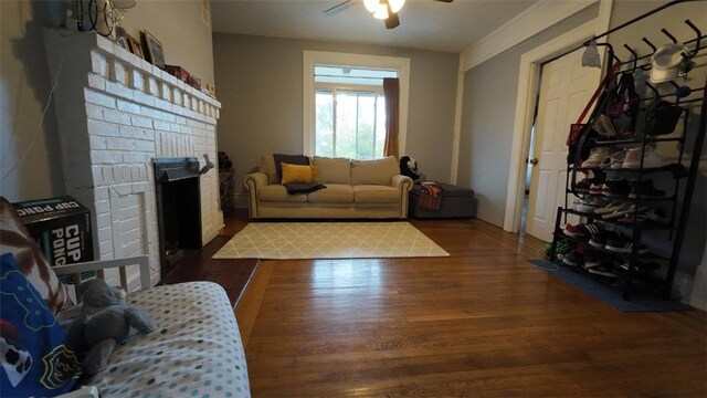 living room featuring a brick fireplace, ceiling fan, and wood finished floors