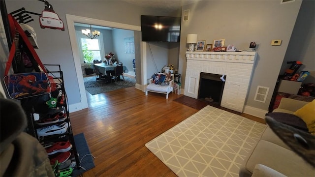 living room with baseboards, an inviting chandelier, visible vents, and wood finished floors