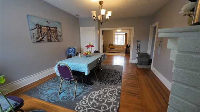 dining area featuring an inviting chandelier, baseboards, visible vents, and wood finished floors