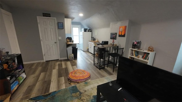 living area featuring vaulted ceiling, baseboards, and wood finished floors