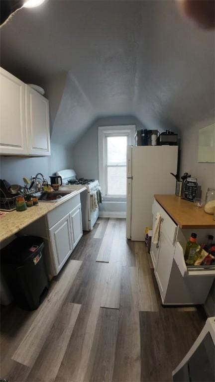 additional living space with lofted ceiling, a sink, and wood finished floors