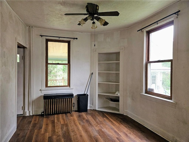 unfurnished room featuring radiator, wood finished floors, and a wealth of natural light