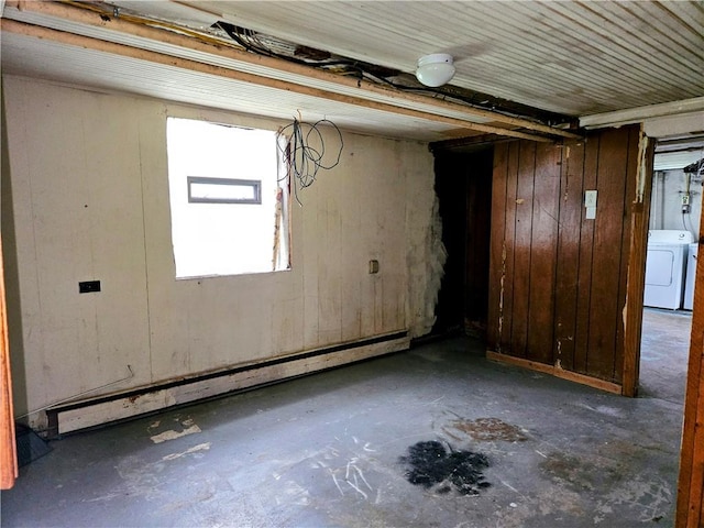 basement featuring washer / dryer, a baseboard heating unit, and wooden walls
