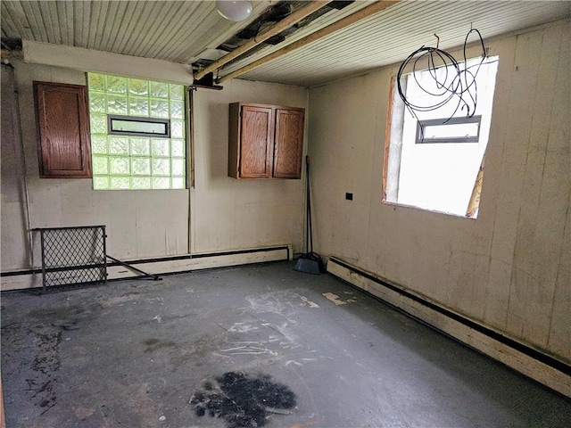 unfurnished room with a healthy amount of sunlight, baseboard heating, and concrete floors