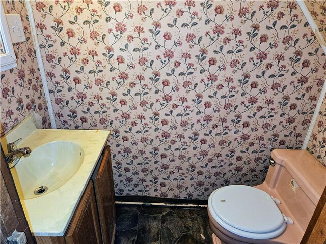 bathroom with vanity, toilet, and wallpapered walls
