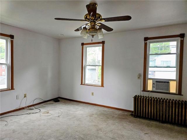 spare room featuring a ceiling fan, baseboards, cooling unit, radiator heating unit, and carpet