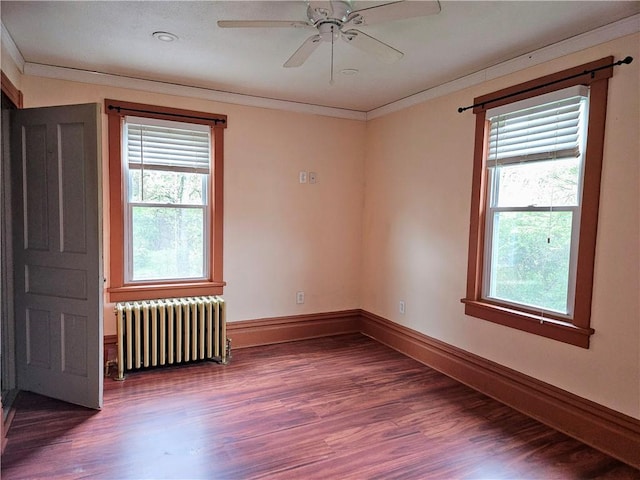 unfurnished room featuring ornamental molding, a healthy amount of sunlight, radiator heating unit, and wood finished floors
