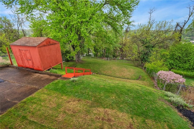 view of yard with fence, a storage unit, and an outbuilding
