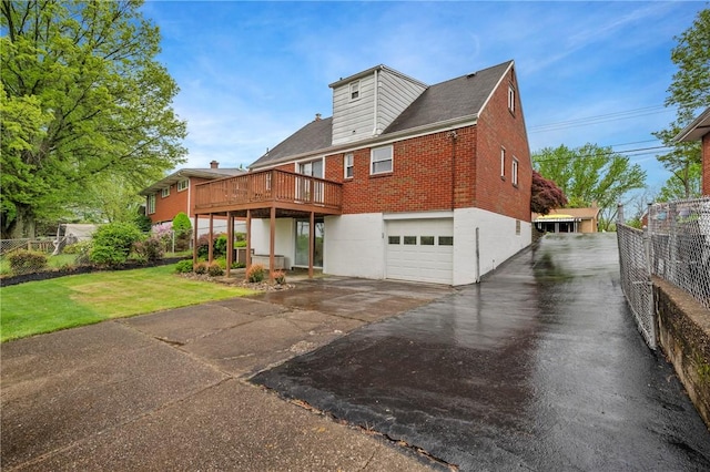 exterior space with fence, a garage, a deck, and brick siding