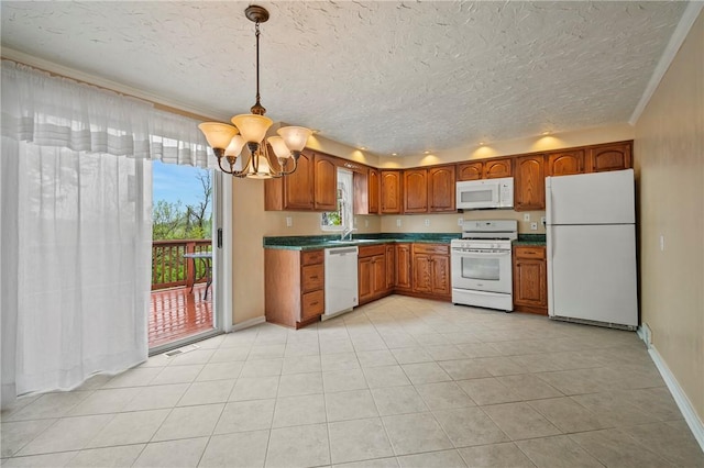 kitchen featuring brown cabinets, dark countertops, an inviting chandelier, white appliances, and baseboards