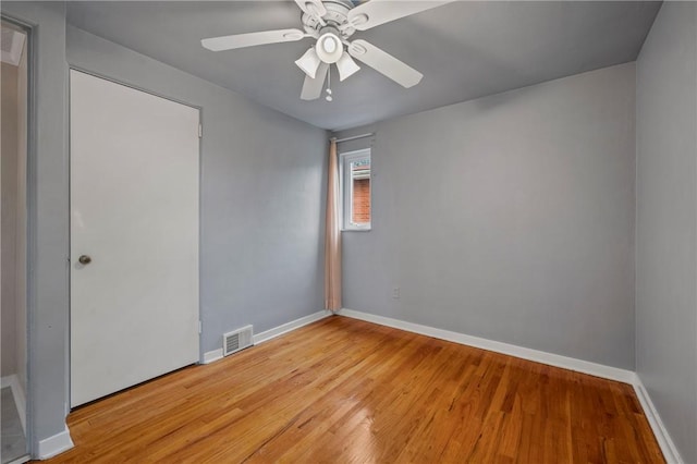 spare room with baseboards, ceiling fan, light wood-type flooring, and visible vents