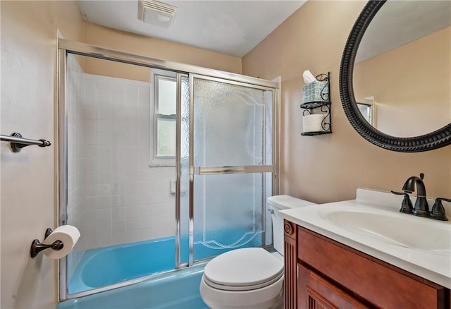 bathroom featuring bath / shower combo with glass door, vanity, toilet, and visible vents