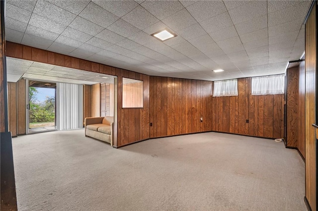 below grade area with wood walls, light carpet, and a healthy amount of sunlight