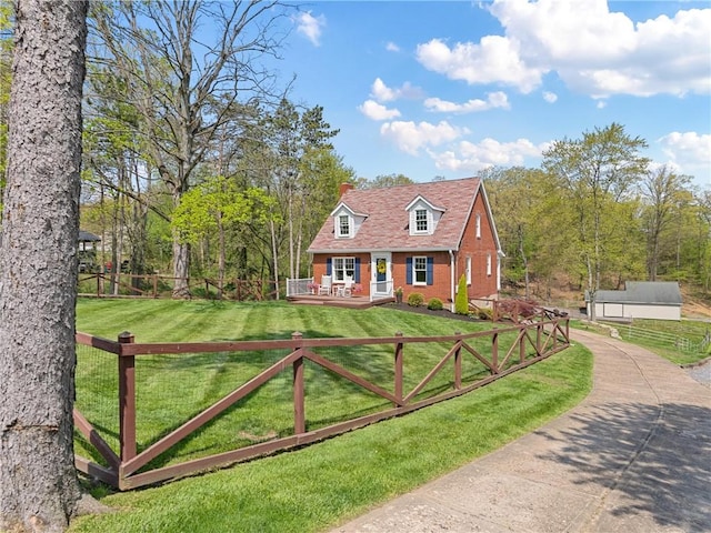 cape cod-style house with fence, a wooden deck, brick siding, and a front yard