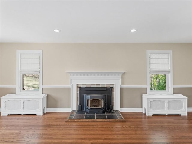 details featuring a wood stove, wood finished floors, baseboards, and recessed lighting