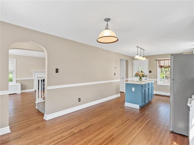 kitchen featuring light wood-style flooring, freestanding refrigerator, baseboard heating, light countertops, and blue cabinets