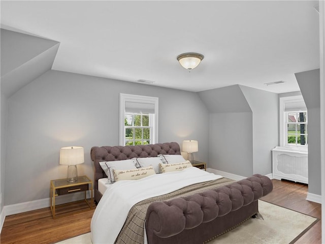 bedroom featuring vaulted ceiling, baseboards, and wood finished floors