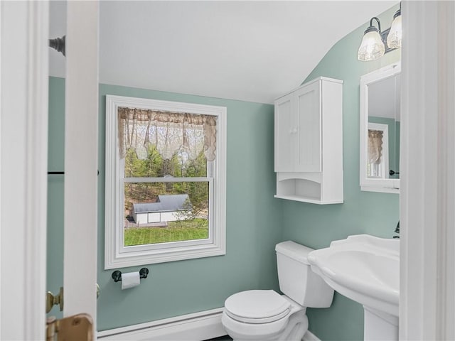 half bath featuring a sink, lofted ceiling, toilet, a baseboard radiator, and baseboards