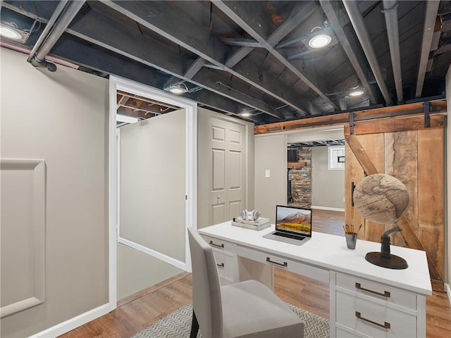 office area featuring built in desk, light wood-style flooring, and baseboards