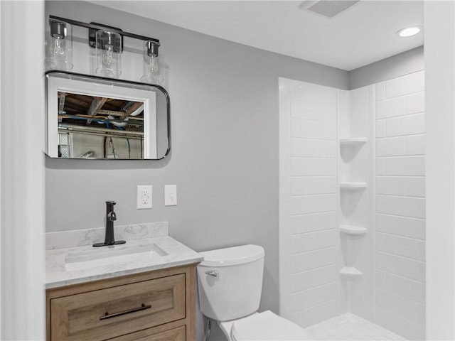 bathroom featuring toilet, vanity, visible vents, and a shower