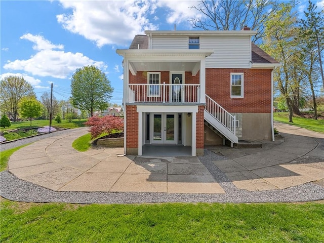 rear view of house featuring a chimney, stairs, french doors, and brick siding
