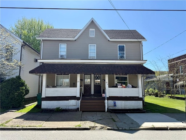 view of front of property featuring a front lawn, roof with shingles, and covered porch