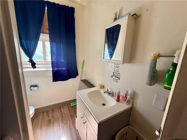 half bath with vanity, toilet, and wood finished floors
