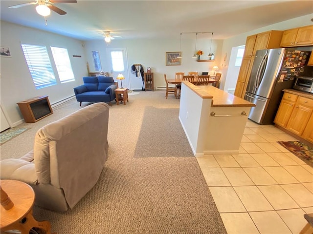 kitchen with freestanding refrigerator, a toaster, ceiling fan, light brown cabinetry, and open floor plan