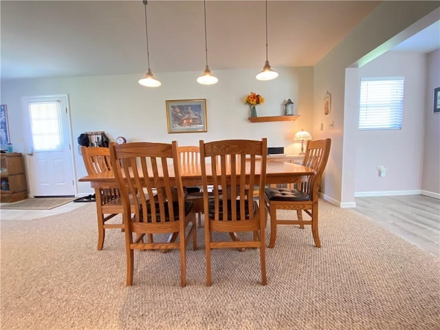 dining area featuring light carpet, a wealth of natural light, and baseboards