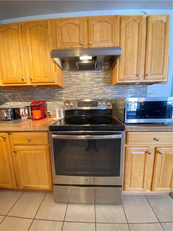 kitchen with backsplash, exhaust hood, appliances with stainless steel finishes, and light tile patterned flooring