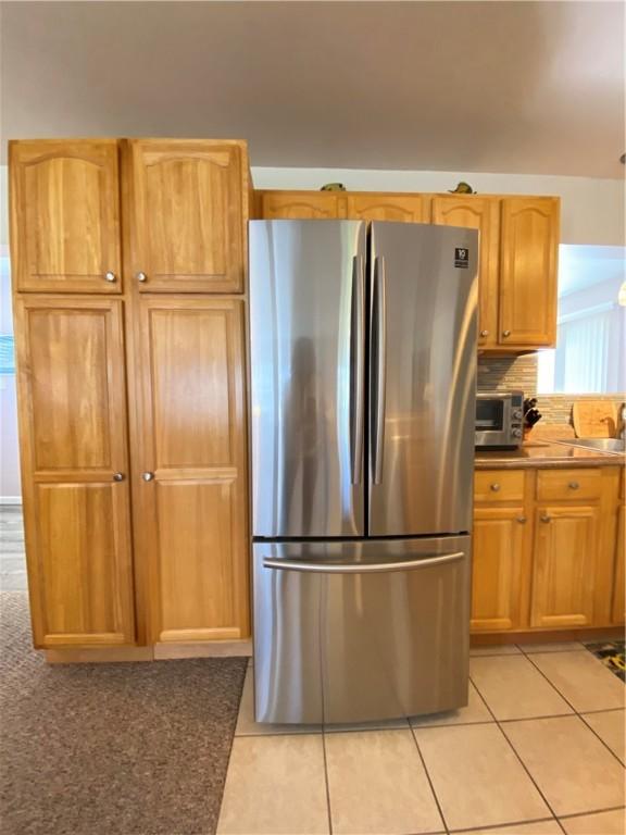 kitchen with freestanding refrigerator and light tile patterned floors