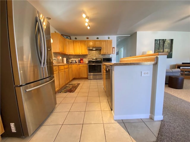 kitchen with under cabinet range hood, decorative backsplash, stainless steel appliances, and light tile patterned flooring