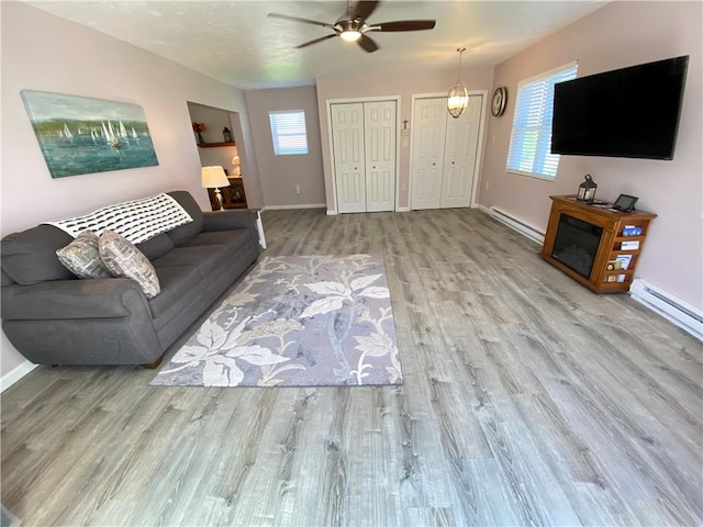 living area featuring ceiling fan, a baseboard radiator, baseboards, and wood finished floors