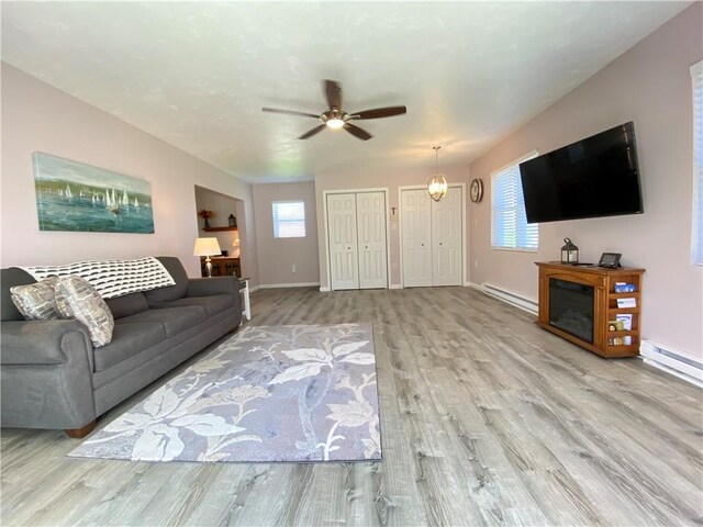 living room with baseboard heating, plenty of natural light, and wood finished floors