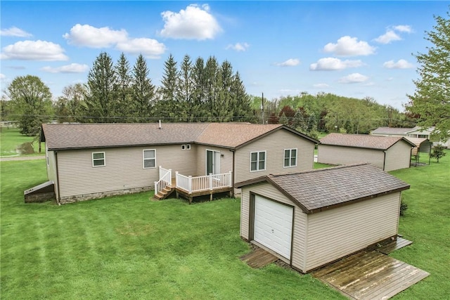 rear view of property with a lawn, a deck, an outbuilding, and roof with shingles