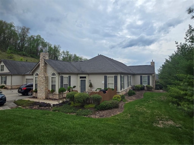 view of front of home featuring a chimney, driveway, and a front lawn