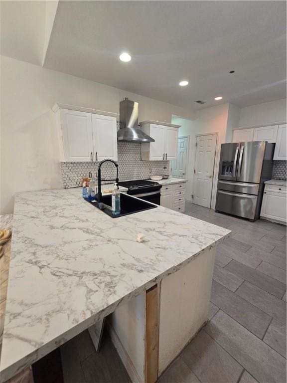 kitchen featuring a sink, a peninsula, range hood, white cabinets, and stainless steel fridge with ice dispenser