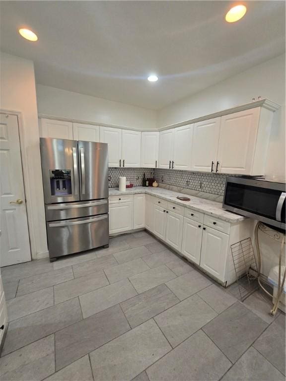 kitchen with white cabinetry, stainless steel appliances, and decorative backsplash